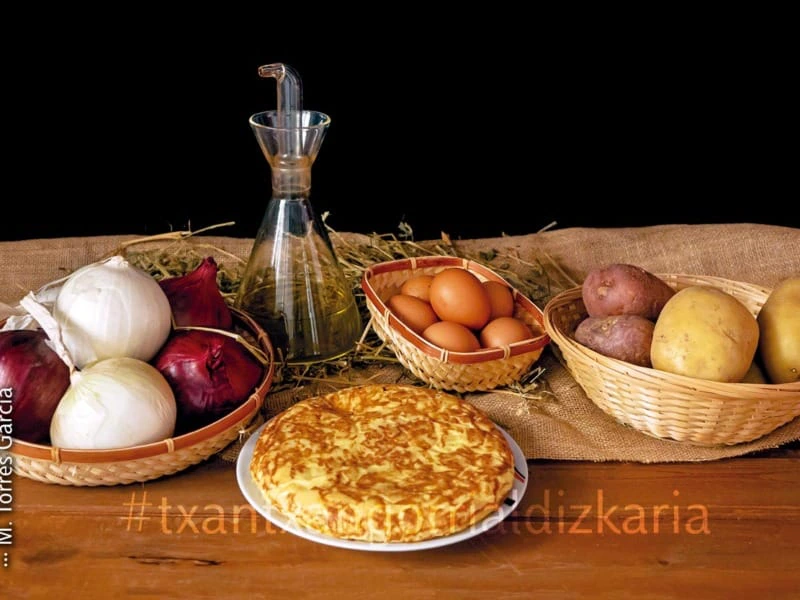 Patata-tortilla bere osagaiez inguratuta, arrautza, olioa, patatak eta tipula.