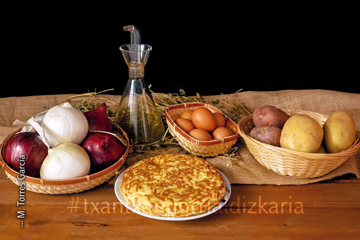 Patata-tortilla bere osagaiez inguratuta, arrautza, olioa, patatak eta tipula.